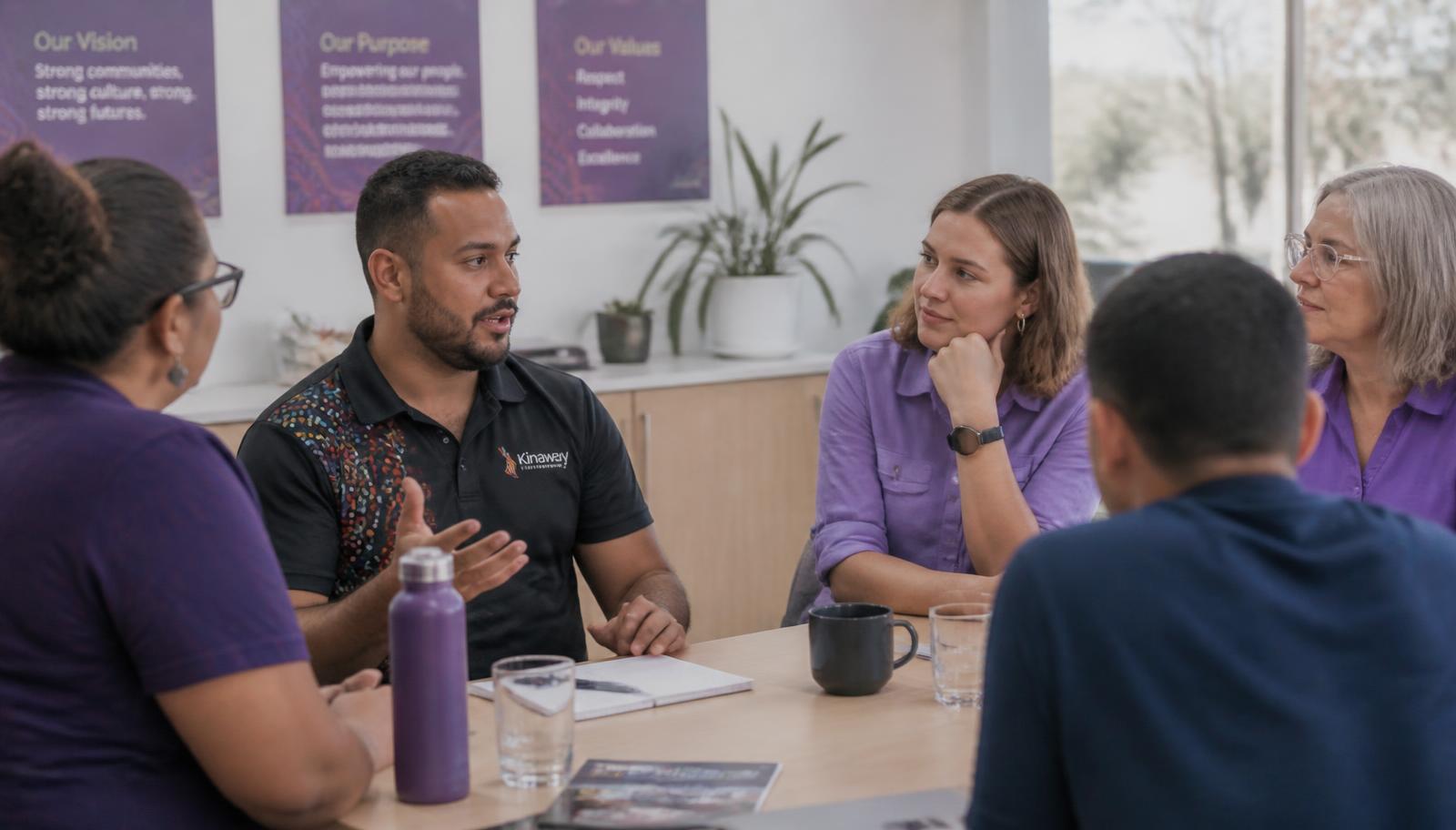 A diverse Australian workplace team talking openly together around a meeting table