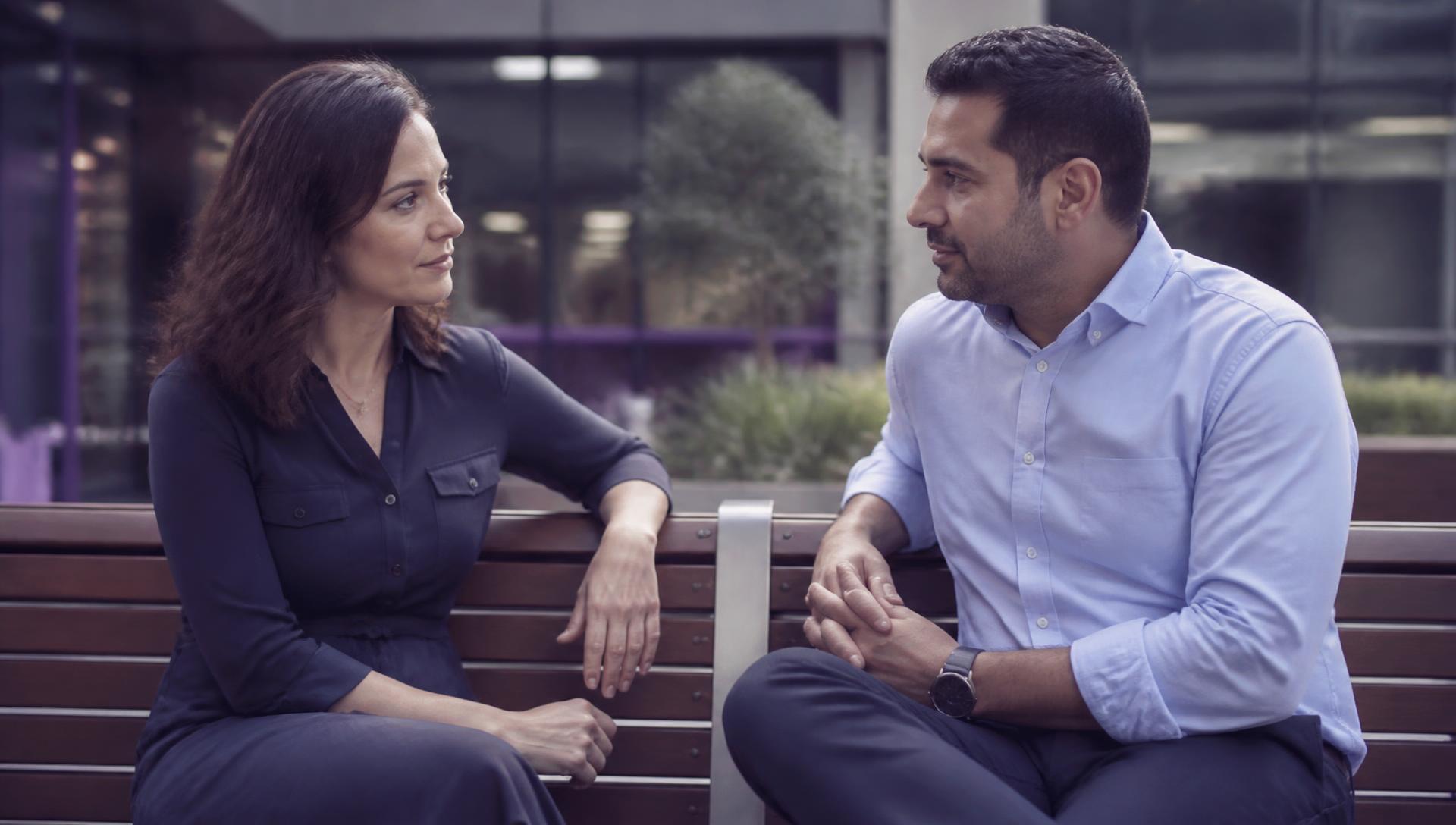 Two colleagues sitting outside a workplace having a calm, supportive conversation